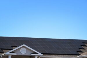 Rooftop with rows of black solar panels installed by St John the Baptist Solar Installers under a clear blue sky.