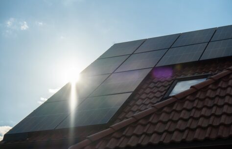 Solar panels installed on a sloped red-tiled roof with sunlight shining behind them, potentially qualifying for the Federal Solar Tax Credit 2026.